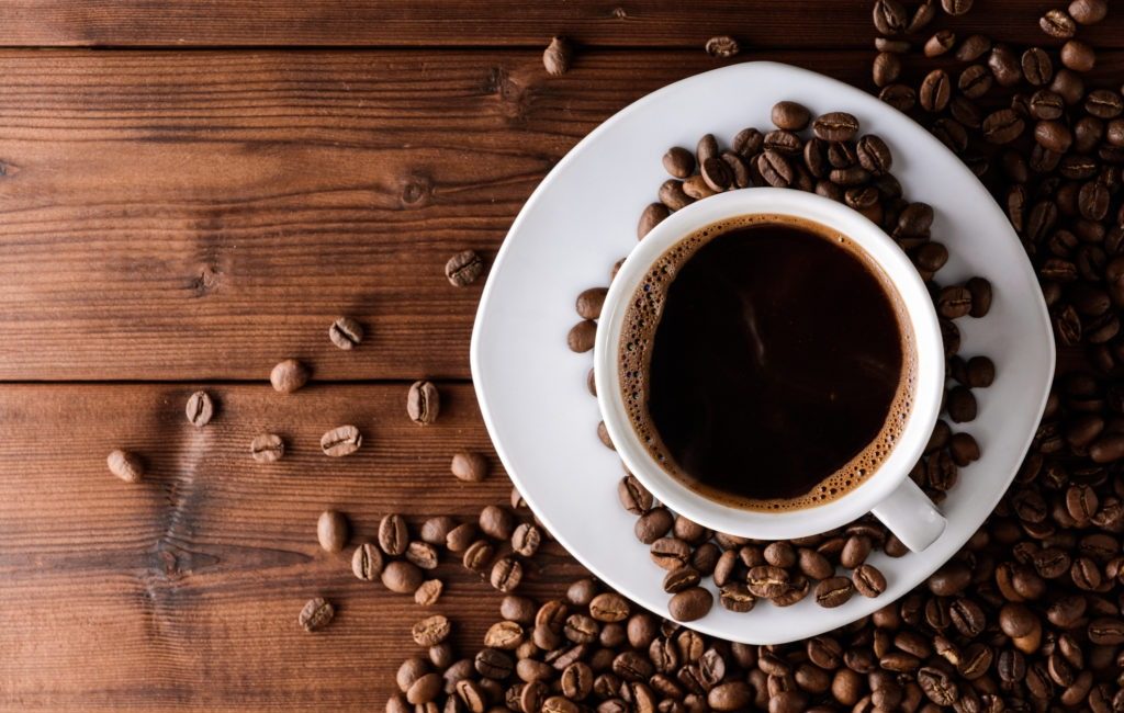 Coffee cup and beans on wooden table. Top view.